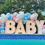 Decorative setup with balloons and 'BABY' letters by a poolside